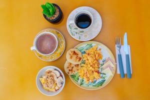 a table with plates of food and a cup of coffee at Casa Flor Hostel & Drinks in Ríohacha
