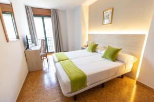 a bedroom with a large bed with green pillows at Hotel Madrid in Pontevedra