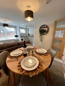 een eettafel met borden en wijnglazen erop bij Chic 2BR Haven - Contemporary Flat in Hoddesdon in Hoddesdon