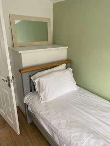 a bed with a white pillow and a mirror at Pontymister Retreat in Risca