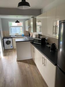 a kitchen with white cabinets and a black refrigerator at Pontymister Retreat in Risca