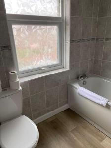 a bathroom with a toilet and a tub and a window at Pontymister Retreat in Risca