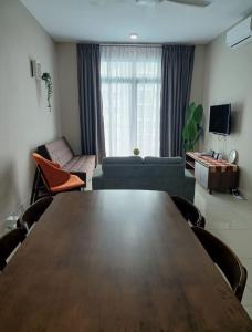 Pangsapuri Desaru Utama Homestay في Bandar Penawar: غرفة معيشة مع طاولة وأريكة