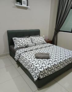 a bed with a black and white comforter and pillows at Pangsapuri Desaru Utama Homestay in Bandar Penawar