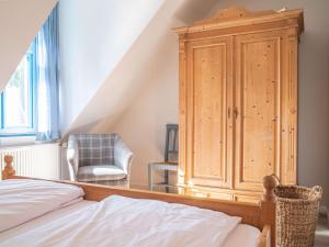 a bedroom with a wooden cabinet and a chair at Ferienhaussiedlung Strandperlen Sanddornhof 5b (Typ V) in Wustrow