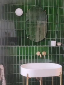 a green tiled bathroom with a sink and a mirror at La Chambre du 21 in Trouville-sur-Mer