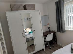 a white mirror in a room with a chair and a bed at Comfortable 2 bedroom house in historic Exeter in Exeter