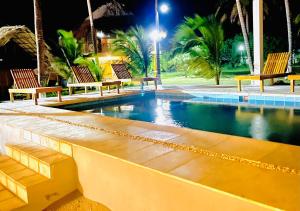 a swimming pool with benches and palm trees at night at Ecohotel Kocoluu in San Bernardo del Viento