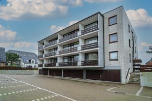a white building with balconies and a parking lot at Bismarck-Koje in Westerland