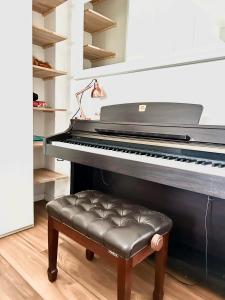 a black piano with a stool in a room at white home near Linate in Segrate