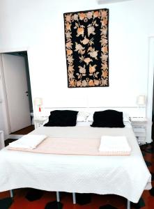 a bedroom with a large white bed with a picture on the wall at Lucretia House in Florence