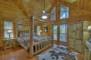 Dormitorio en cabaña de madera con cama y ventilador de techo en Crooked Creek View Near Ocoee River, With Hot Tub, en Copperhill