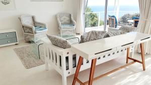 a living room with a white table and chairs at Stunning Simonstown Apartment in Simonʼs Town