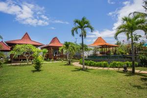 a resort with palm trees and houses with a yard at Pondooks Joglo in Nusa Lembongan