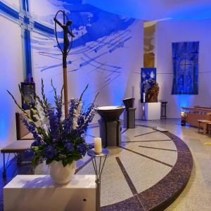 eine Lobby mit einer Vase aus Blumen und einer Kerze in der Unterkunft Spectrum Kirche Exerzitien-und Bildungshaus auf Mariahilf in Passau