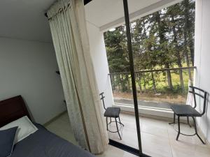 1 Schlafzimmer mit einem Bett, einem Fenster und 2 Stühlen in der Unterkunft Hotel Playa Blanca in Tota