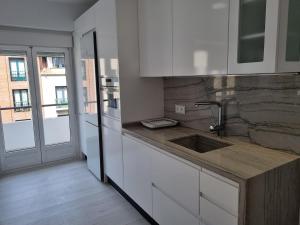 una cocina con armarios blancos y fregadero en 131A - Espectacular apartamento 8 personas Puerto, en Gijón