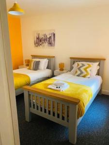two beds in a room with yellow and white at Goldcroft in Abertillery