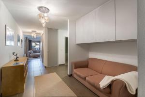 een woonkamer met een bruine bank en een keuken bij Les 4 Elements - Apt A11 - BO Immobilier in Châtel