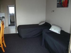 Habitación pequeña con 2 camas y silla en Sun Valley Motel, en Wellsford