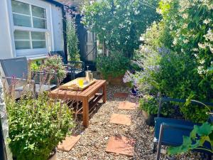 um jardim com uma mesa de madeira e algumas plantas em Holbrook House em Kent