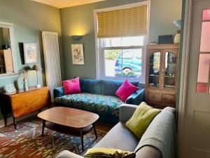 uma sala de estar com um sofá azul e almofadas cor-de-rosa em Holbrook House em Kent