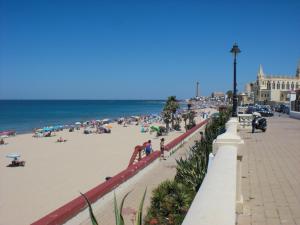 un grupo de personas en la playa cerca del océano en Penthouse Sleeps 4 with Private Garden, en Chipiona