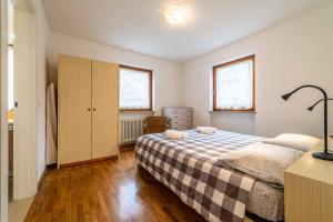 1 dormitorio con 1 cama, vestidor y 2 ventanas en Appartamento Dolomia, en Caprile