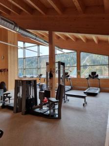 a gym with several treadmills and machines in a room with windows at Hotel Matschner in Ramsau am Dachstein