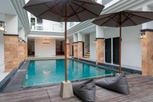 a swimming pool with two umbrellas in a building at Guyana Hotel in Kuta