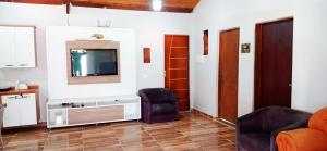 a living room with a television and two chairs at Incrivel chacara com pisc e churrasq em Extrema MG in Extrema