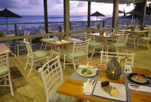 een restaurant met tafels en stoelen en uitzicht op de oceaan bij Bougainvillea Barbados in Christ Church