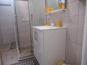 ein weißes Bad mit einem Waschbecken und einer Dusche in der Unterkunft L'hibiscus By Nid'Ouest - Grand T3 - Parking privé in Le Lamentin