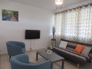 sala de estar con sofá, 2 sillas y TV en L'hibiscus By Nid'Ouest - Grand T3 - Parking privé, en Le Lamentin