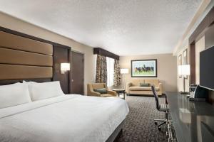 a hotel room with a bed and a living room at Holiday Inn Louisville East - Hurstbourne by IHG in Louisville