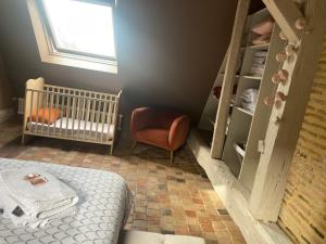 een babykamer met een wieg en een stoel bij Chambre Alix in La Flèche