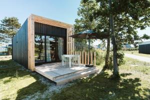 a small house with a table and an umbrella at Vakantiepark De Klepperstee in Ouddorp