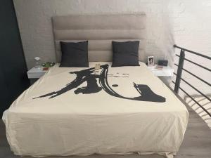 a bed with a black and white comforter on it at Loft Apartment Cape Town The Waterkant in Cape Town