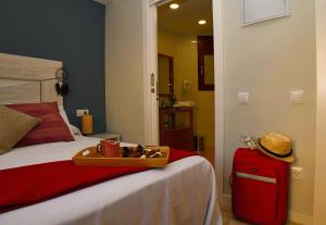 um quarto com uma cama com uma mala e um chapéu em Can Mir Badalona em Badalona