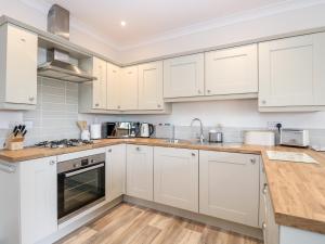 a kitchen with white cabinets and wooden floors at Robin's Nest in Brisley