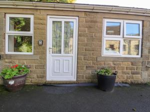 a brick house with a door and two potted plants at Bronte Cottage in Keighley