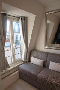 un soggiorno con divano e una grande finestra di Paris 17 - Batignolles - Studio 10 m2 - 1 room - Single occupancy - near Champs Elysées & Montmartre & Dpt stores a Parigi