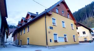 a yellow building with snow on the ground at Apartmaji Pr' Kopavank in Rateče