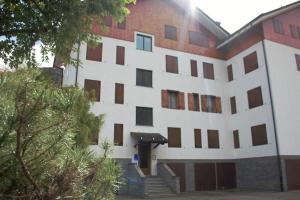 スコペッロにある[FREE WIFI] Elegante bilocale vicino alle pisteの茶色の窓と階段が特徴の白い大きな建物