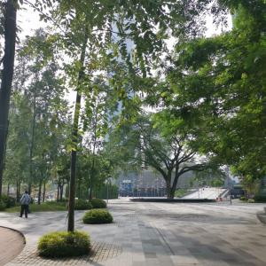 a park with trees and a person walking down a street at Hotel Aman Kuala Lumpur in Kuala Lumpur