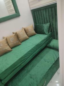 un sofá verde con almohadas encima en SUPERBE appart 2 ch au résidence balnéaire colina smir, en M'diq