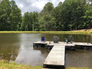 two chairs and a table on a dock over a lake at Tentrr Signature Site - 6 Ponds Farm Glamping in Morganton