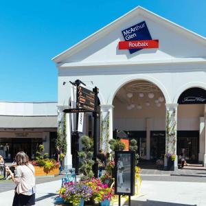 a woman standing in front of a shopping center at HOTEL DU CENTRE in Roubaix