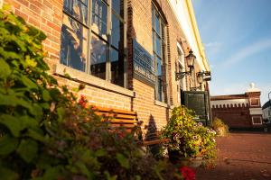 a bench in front of a brick building with flowers at Boutique Hotel De Oude Veste in Hellevoetsluis