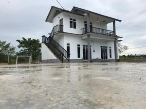 une maison avec un parking inondé devant elle dans l'établissement Rumah Sawah Homestay Pasir Puteh, à Pasir Puteh